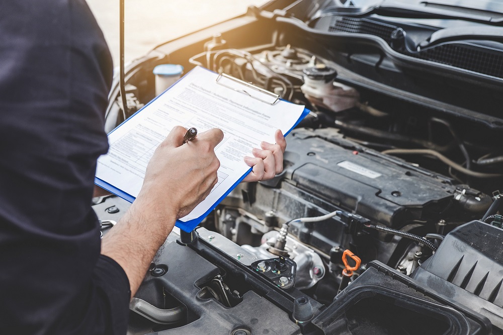 Service Tech with Clipboard Checking Hood of Car