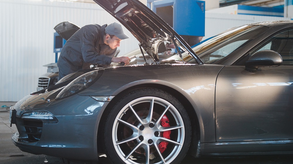 Mechanic checking under hood of car