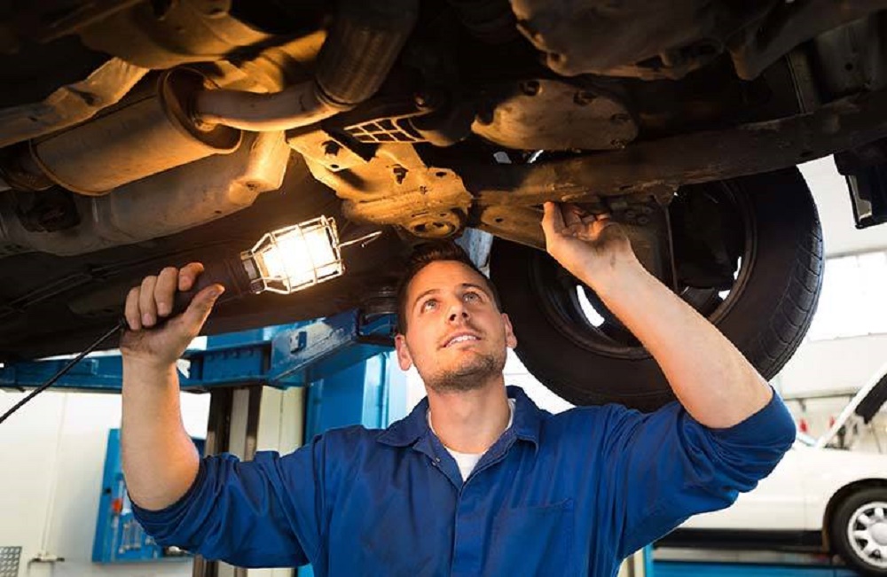 Car Tech Inspecting Under Used Car