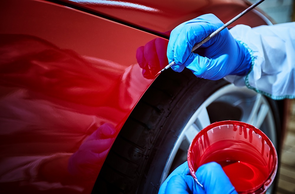 Man Touching Up a Red Car with a Fine Paintbrush