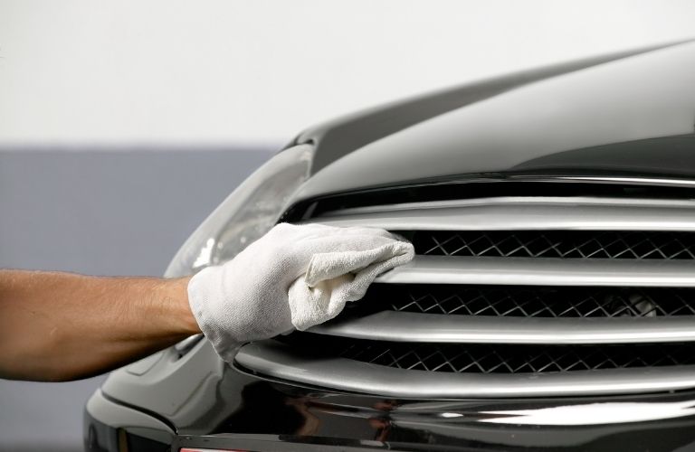 a technician cleaning the grille of a car