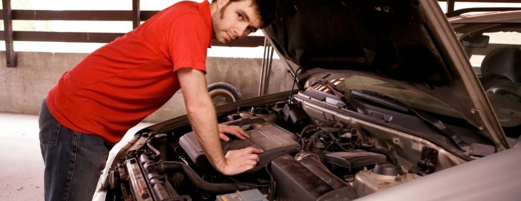 a technician inspecting under the hood of a car